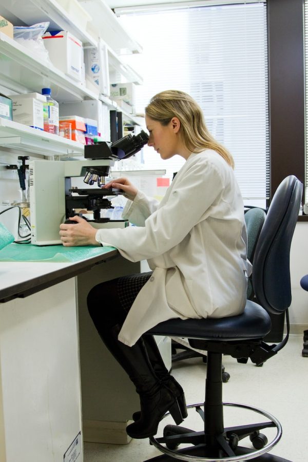 femme avec un microscope dans un laboratoire génétique