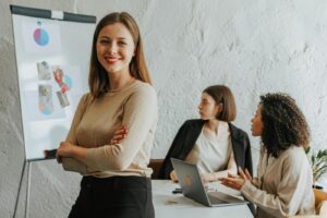 Une femme confiante souriant dans un bureau moderne avec des collègues au travail.