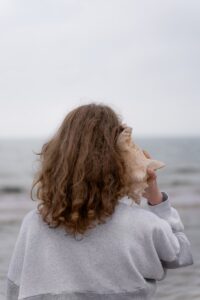 une femme tenant un coquillage devant son visage