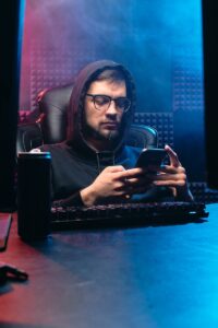 Un homme dans un bureau sombre utilisant un smartphone, incarnant des thèmes cybernétiques et technologiques.