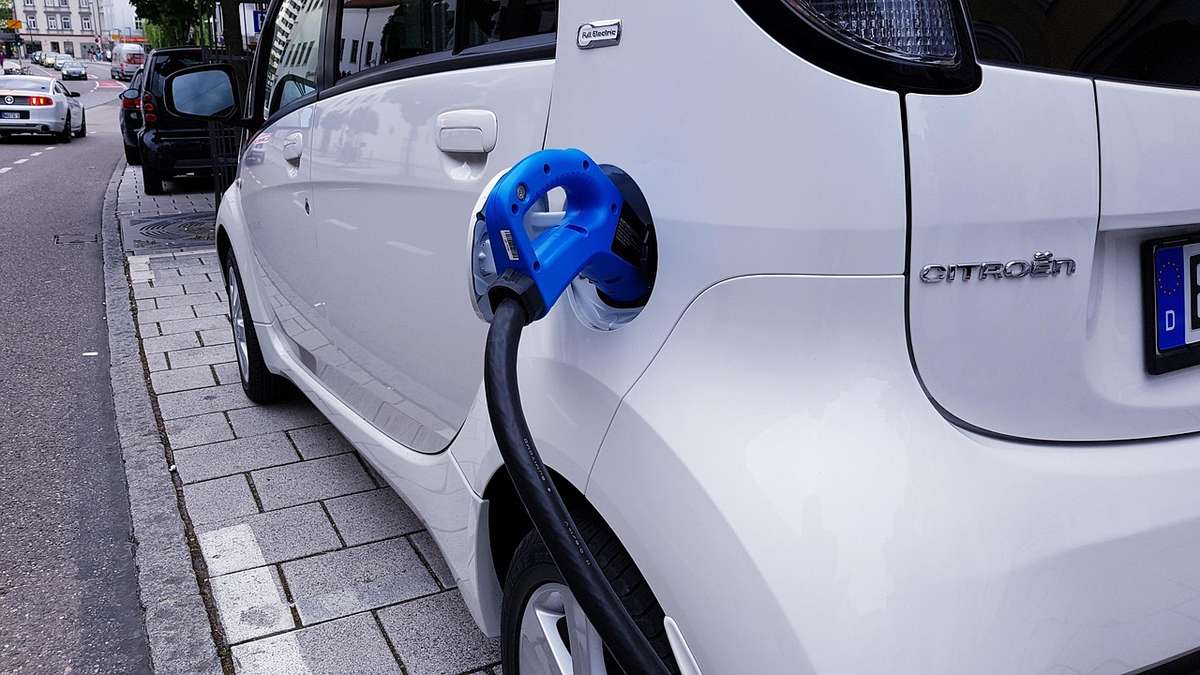 Citroën blanche en recharge avec câble branché sur trottoir urbain