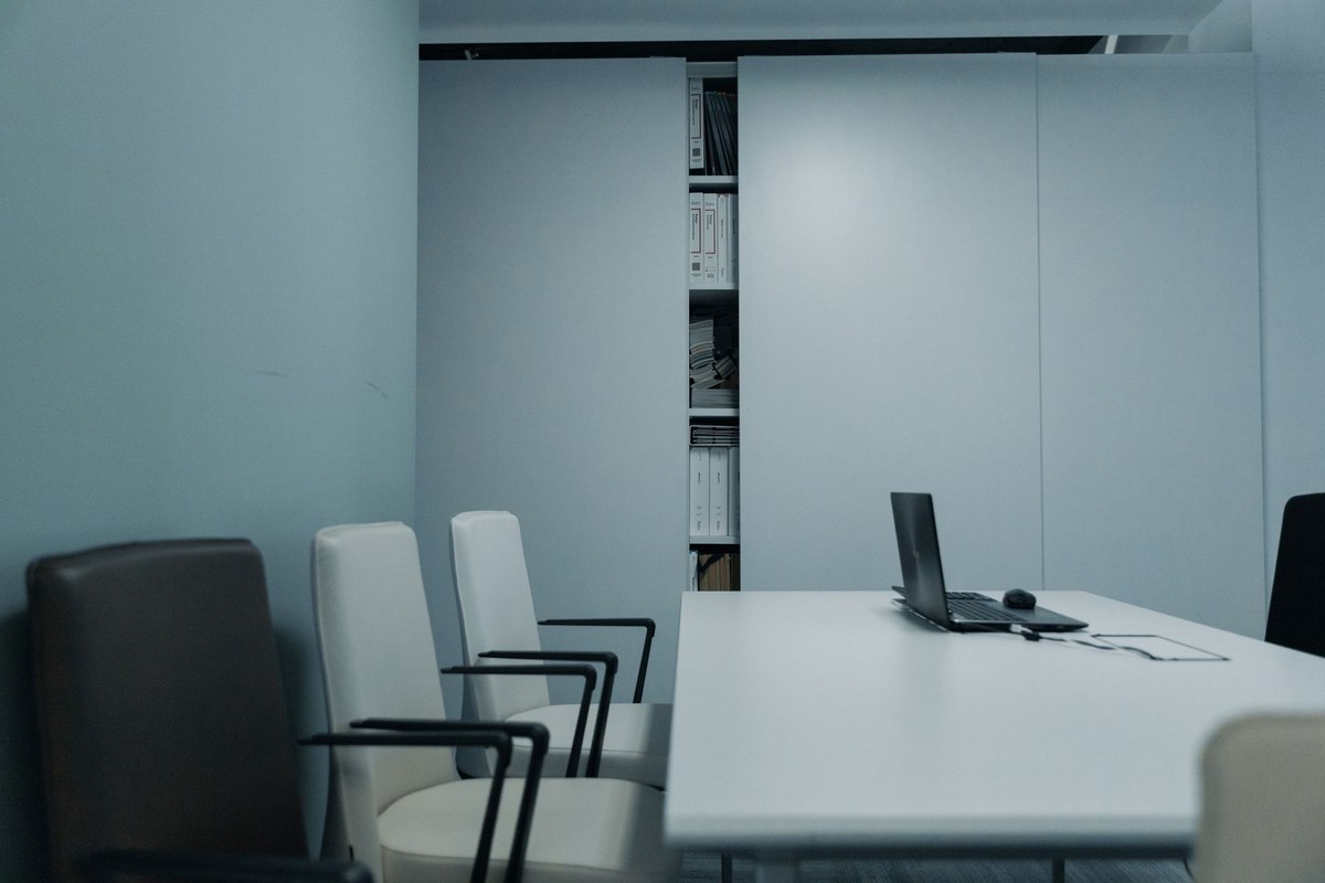 Salle de réunion avec table, chaises, ordinateur portable et étagère