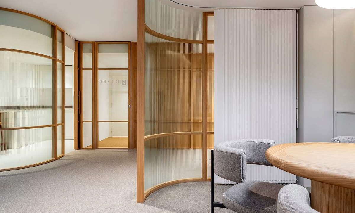 Salle de réunion contemporaine avec table ronde, chaises, cloisons en verre et bois