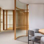 Salle de réunion contemporaine avec table ronde, chaises, cloisons en verre et bois