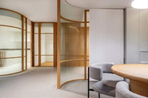 Salle de réunion contemporaine avec table ronde, chaises, cloisons en verre et bois
