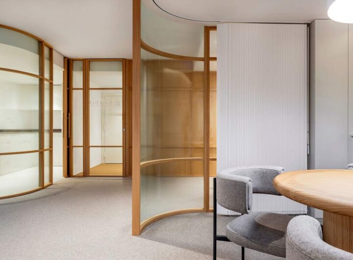 Salle de réunion contemporaine avec table ronde, chaises, cloisons en verre et bois