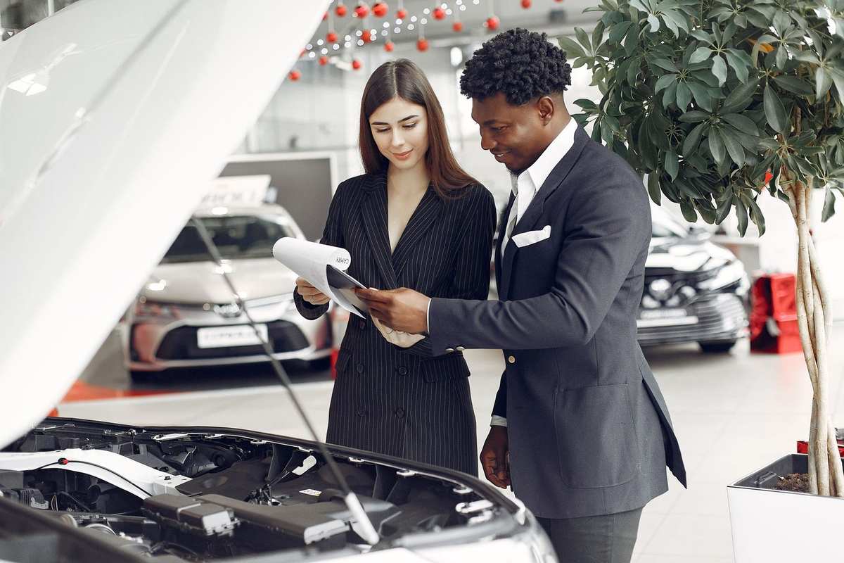 Professionnels analysent des documents près d'une voiture dans un showroom