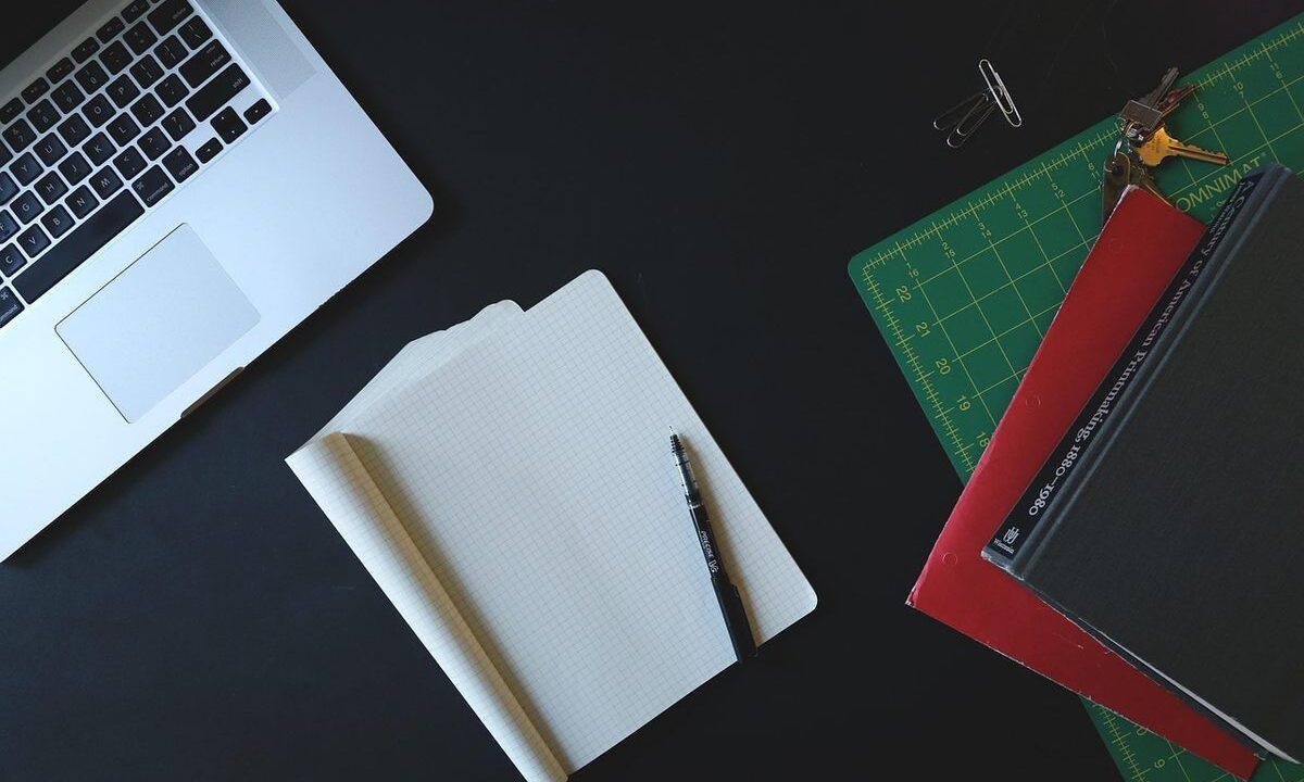 Espace de travail avec ordinateur portable, papier blanc, stylo et règle de dessin sur fond noir