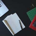 Espace de travail avec ordinateur portable, papier blanc, stylo et règle de dessin sur fond noir