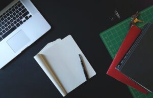 Espace de travail avec ordinateur portable, papier blanc, stylo et règle de dessin sur fond noir