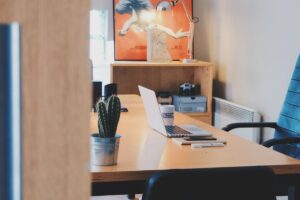 Un bureau avec ordinateur, cactus, chaise et tableau mural