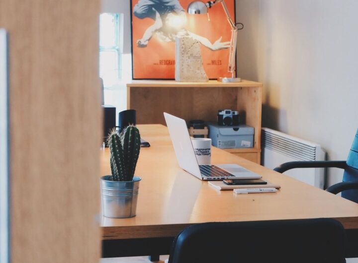 Un bureau avec ordinateur, cactus, chaise et tableau mural