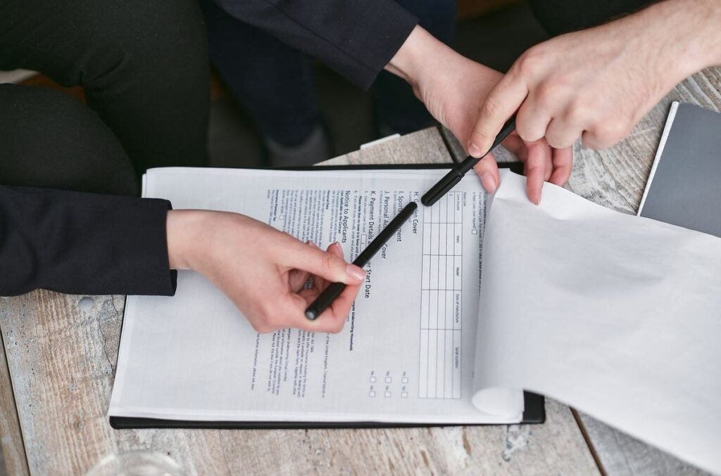 Deux mains signant un document sur une table en bois