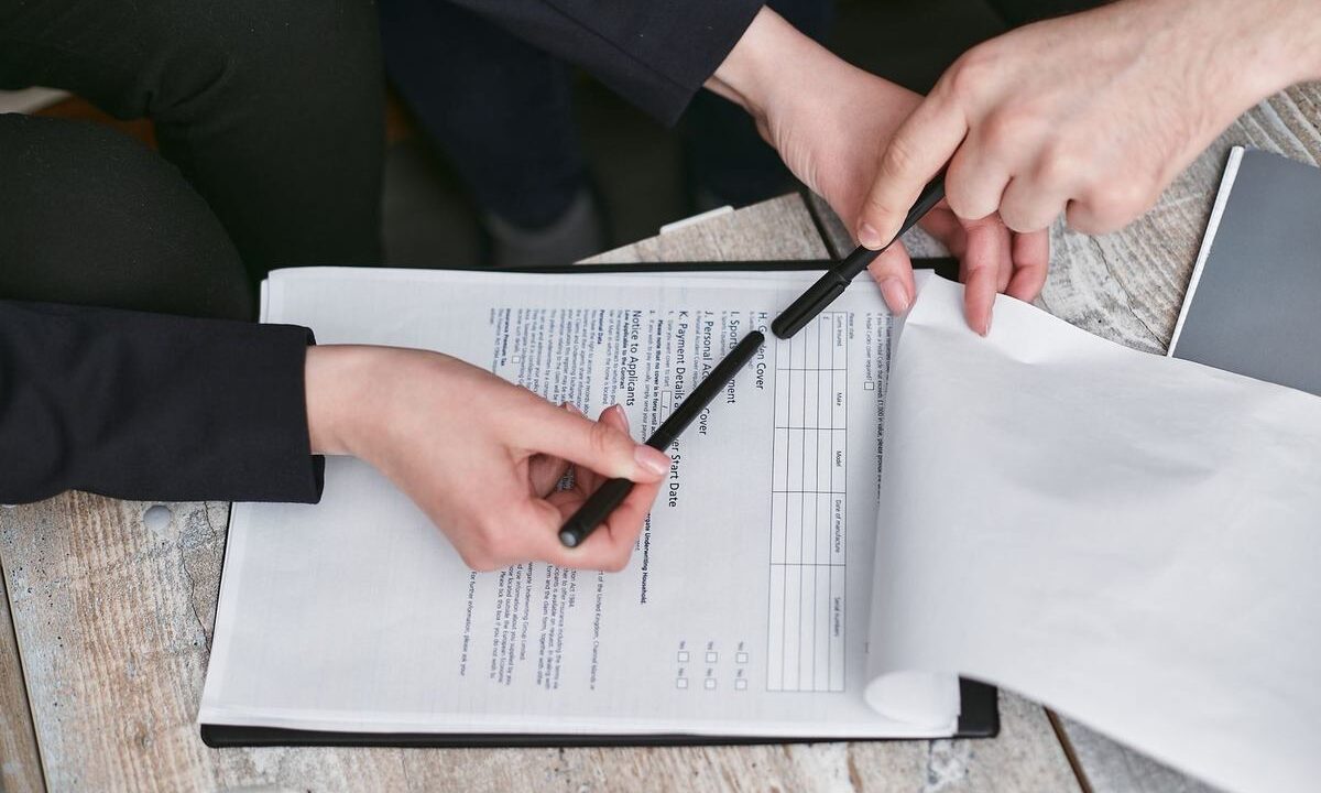 Deux mains signant un document sur une table en bois