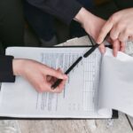 Deux mains signant un document sur une table en bois