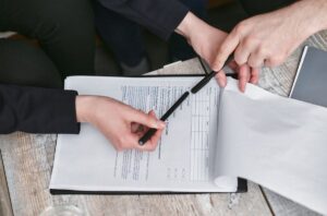 Deux mains signant un document sur une table en bois