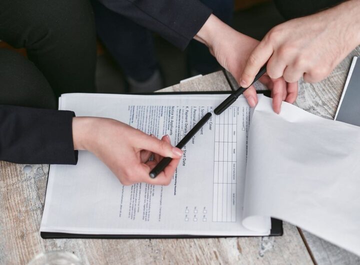 Deux mains signant un document sur une table en bois